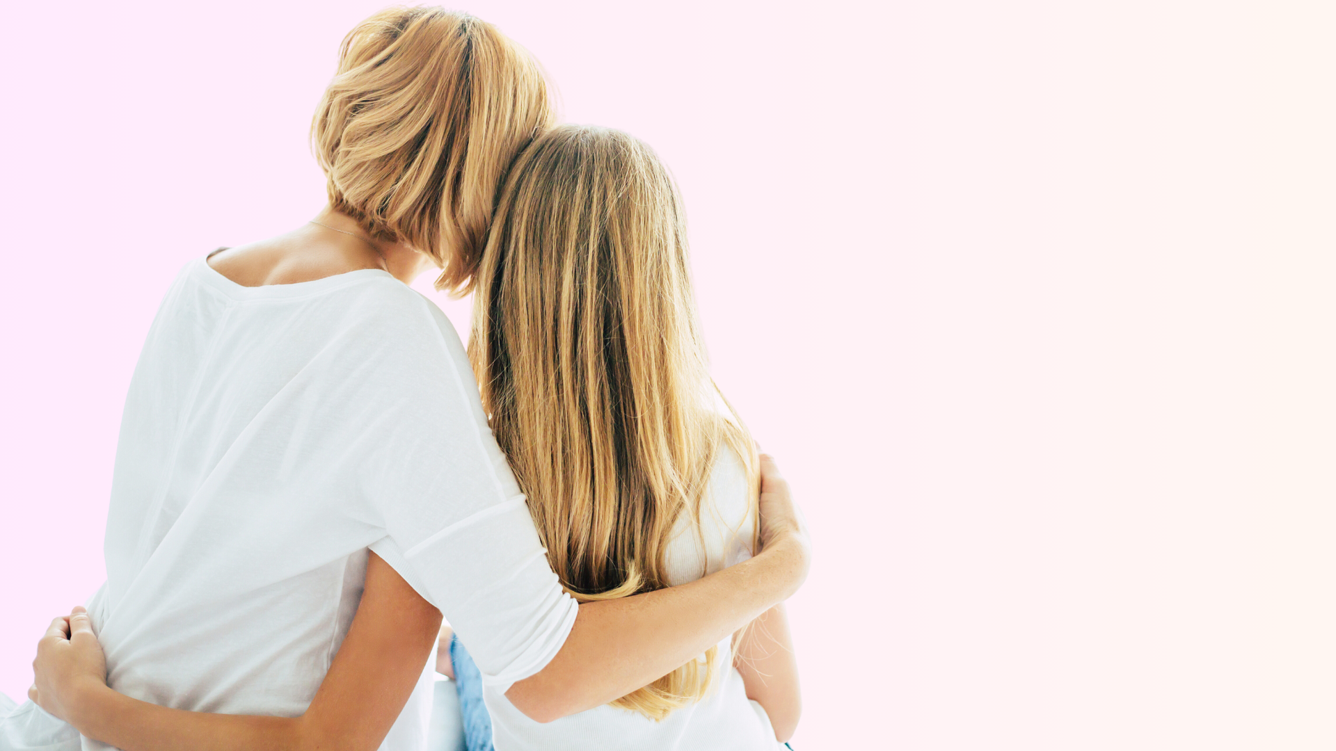 A mother and daughter sit with their backs to the camera and their arms around each other. The mother has short blonde hair, the daughter has long blonde hair. Both are wearing white shirts.