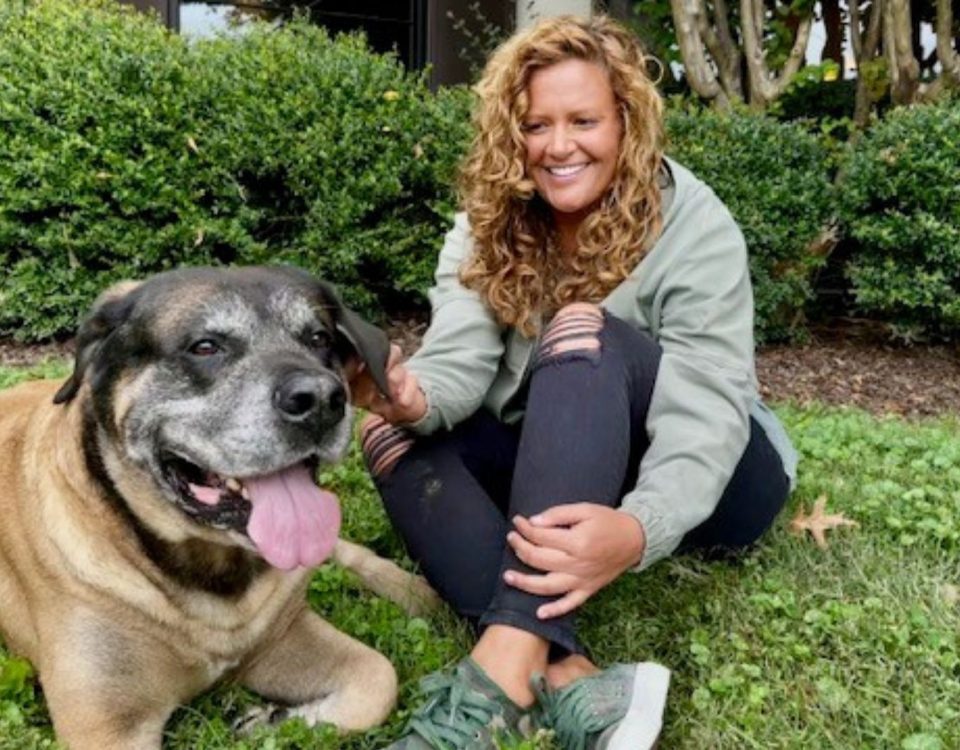 Jill Rainford sits on a patch of grass with an English Mastiff named Samson, who is laying down.