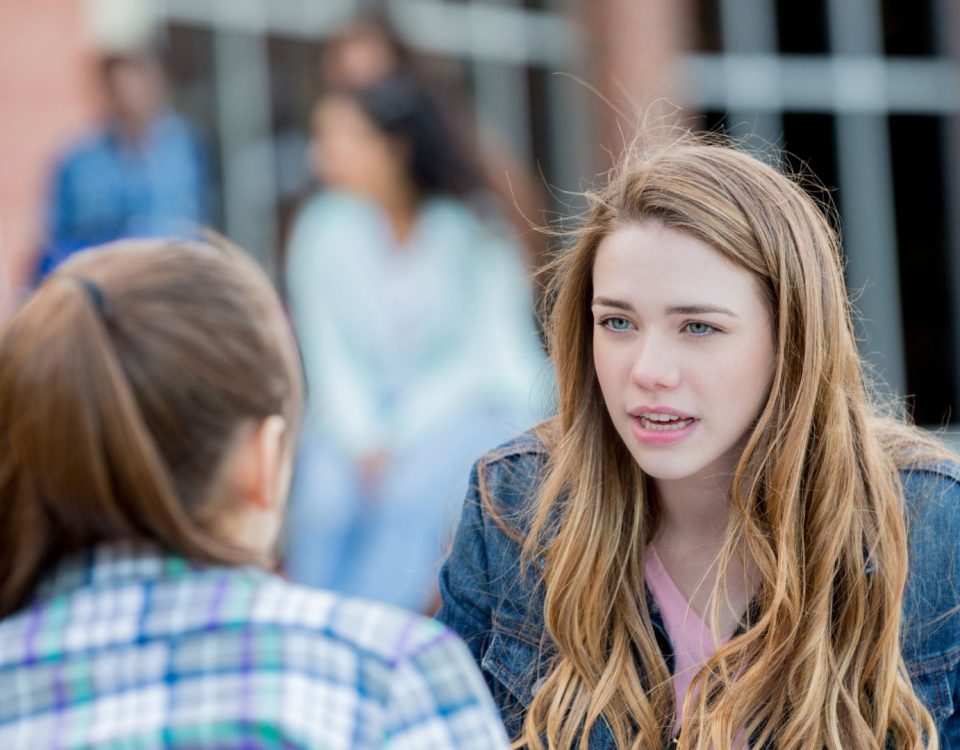 A girl talks with her mom about suicide. They appear to be outdoors, possibly by a school.