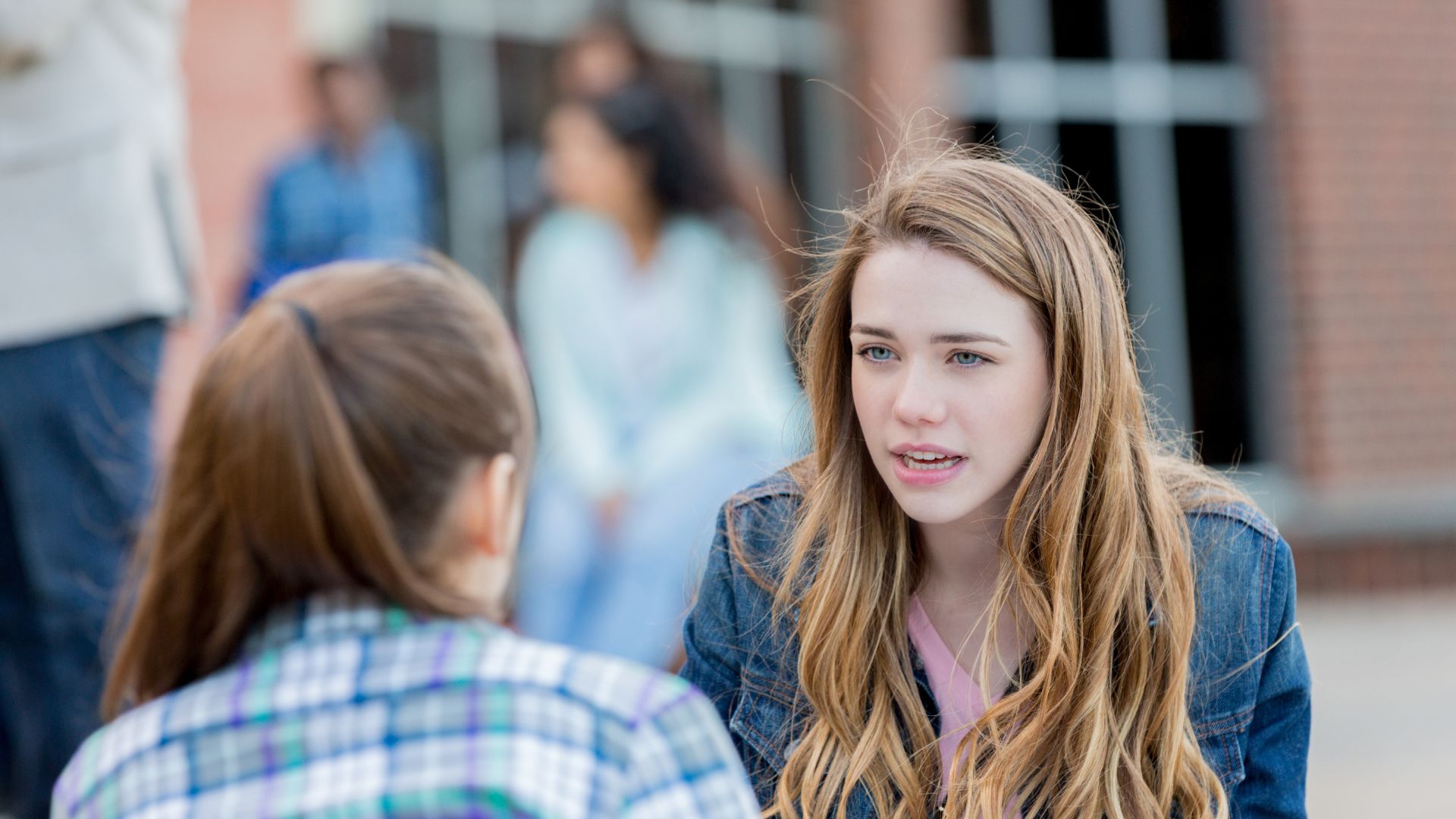 A girl talks with her mom about suicide. They appear to be outdoors, possibly by a school.