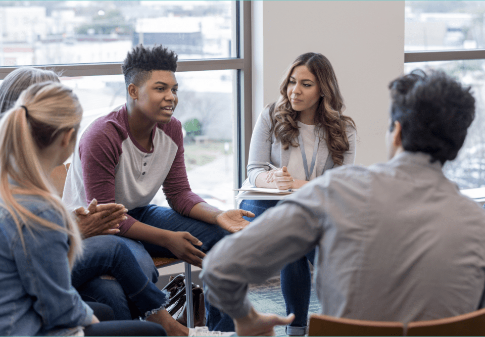 How long therapy takes to work depends on a child's diagnosis and the intensity of treatment. In this image four teens sit in a circle while a therapist moderates.