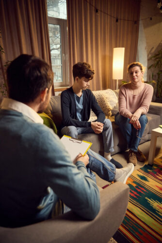 Teenager in therapy session with psychiatrist and parent 