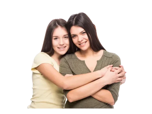 Two young women smiling and embracing.