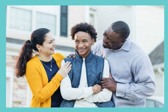 An African-American mother and father stand on either side of their teenage son, expressing joy about his mental health. This photo represents the importance of mental health treatment for teens