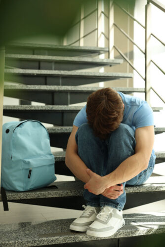Depressed teen sitting on stairs with head on knees