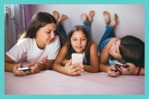 three adolescent girls looking at their phones and interacting with social media